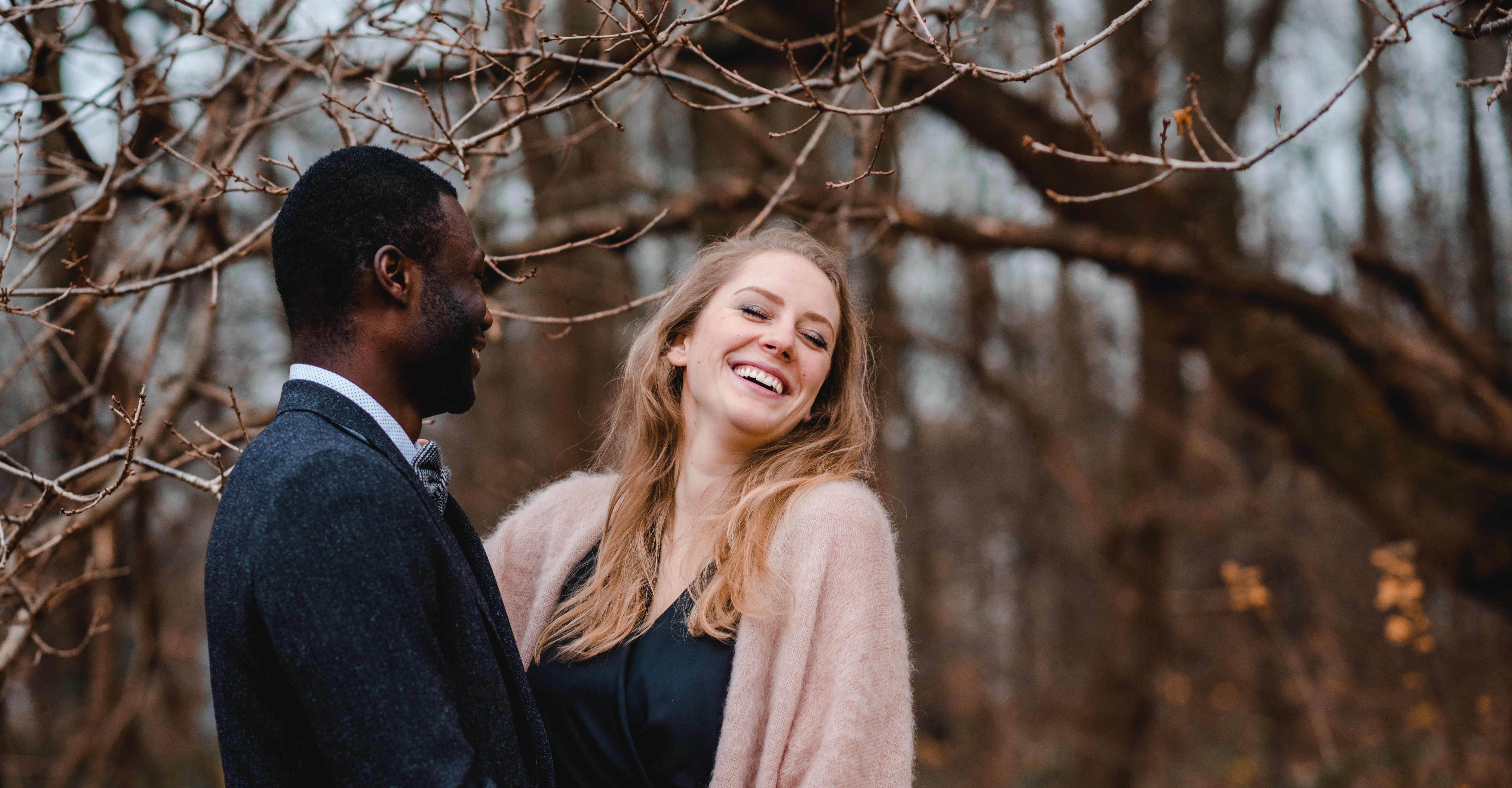 Lachendes Paar bei einem Verlobungs-Fotoshooting in einem Wald bei Düsseldorf.