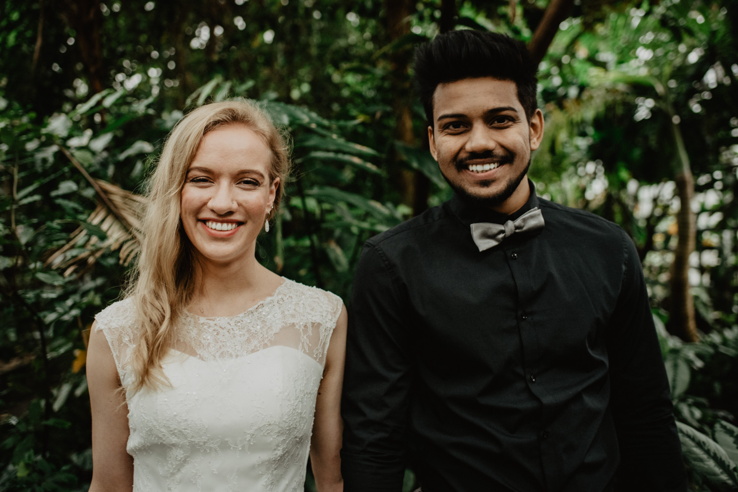 Ein Brautpaar steht frontal zur Kamera und lacht.