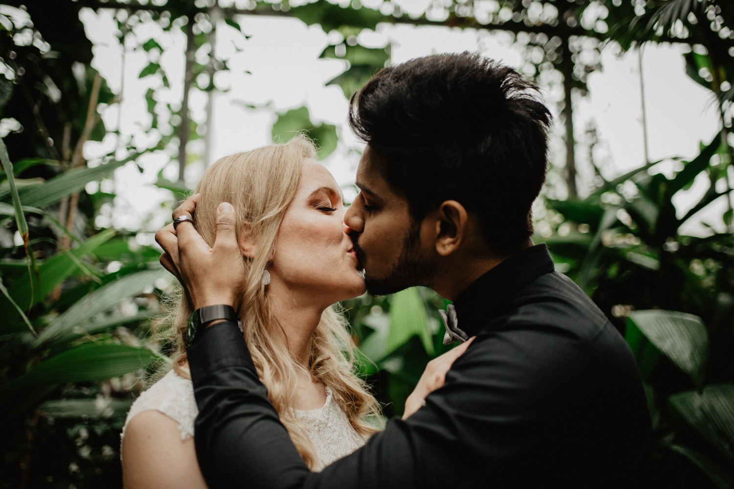 Ein Hochzeitspaar küsst sich im Botanischen Garten Bonn.