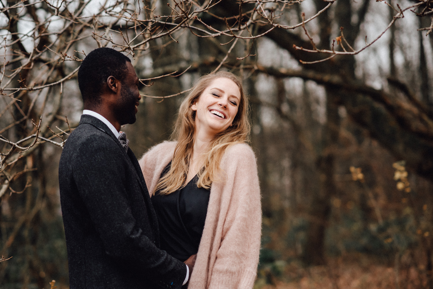 Lachendes Paar bei einem Verlobungs-Fotoshooting in einem Wald bei Düsseldorf. 