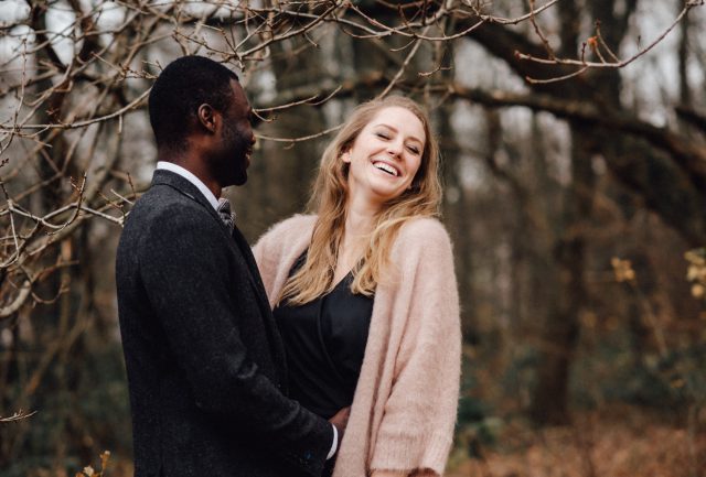Lachendes Paar bei einem Verlobungs-Fotoshooting in einem Wald bei Düsseldorf.