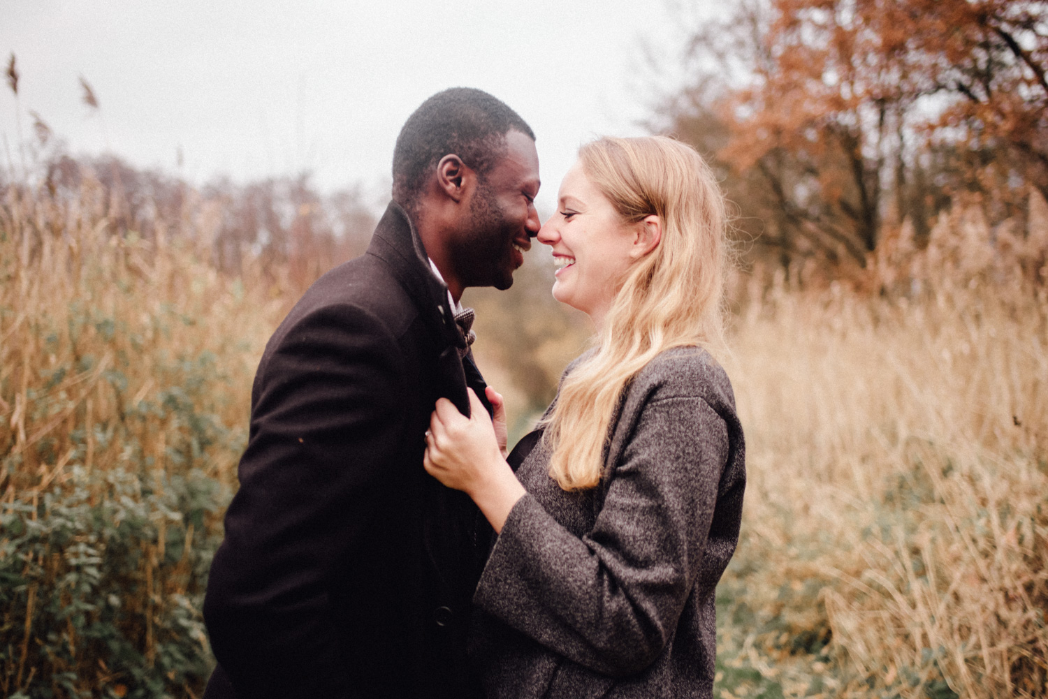 Multikulturelles Paar lacht sich bei einem Verlobungsshooting in Düsseldorf an.