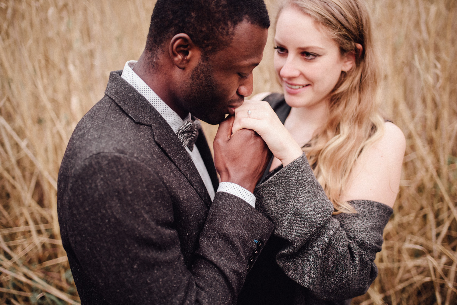 Mann küsst die Hand seiner Verlobten, an der sie einen Verlobungsring trägt.