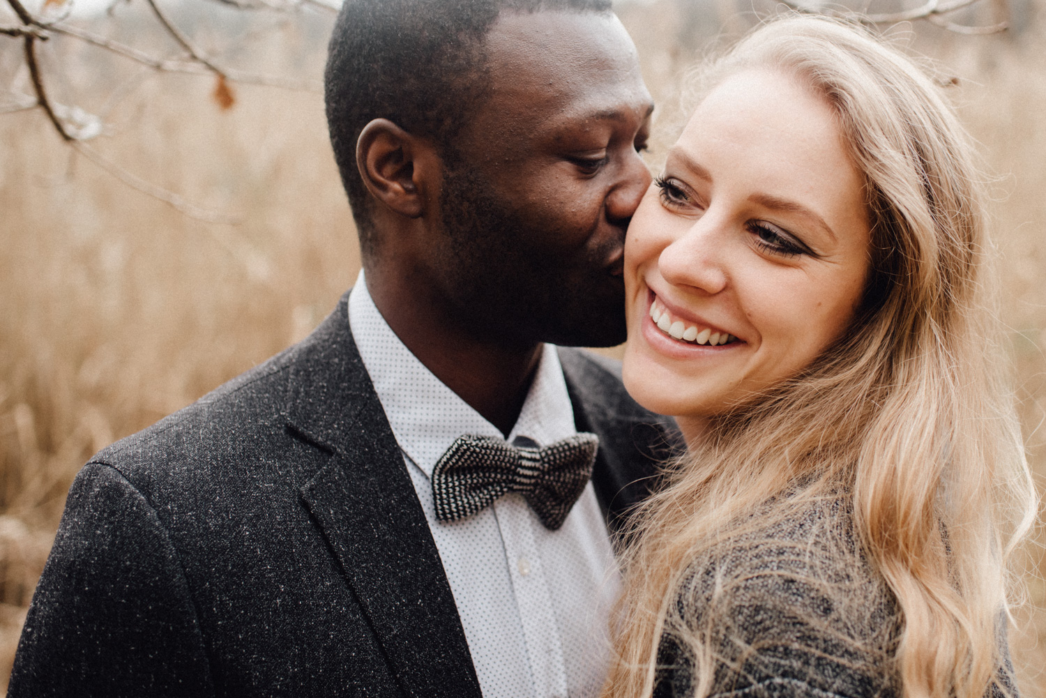 Ein Mann küsst seine Verlobte auf die Wange während sie glücklich lacht