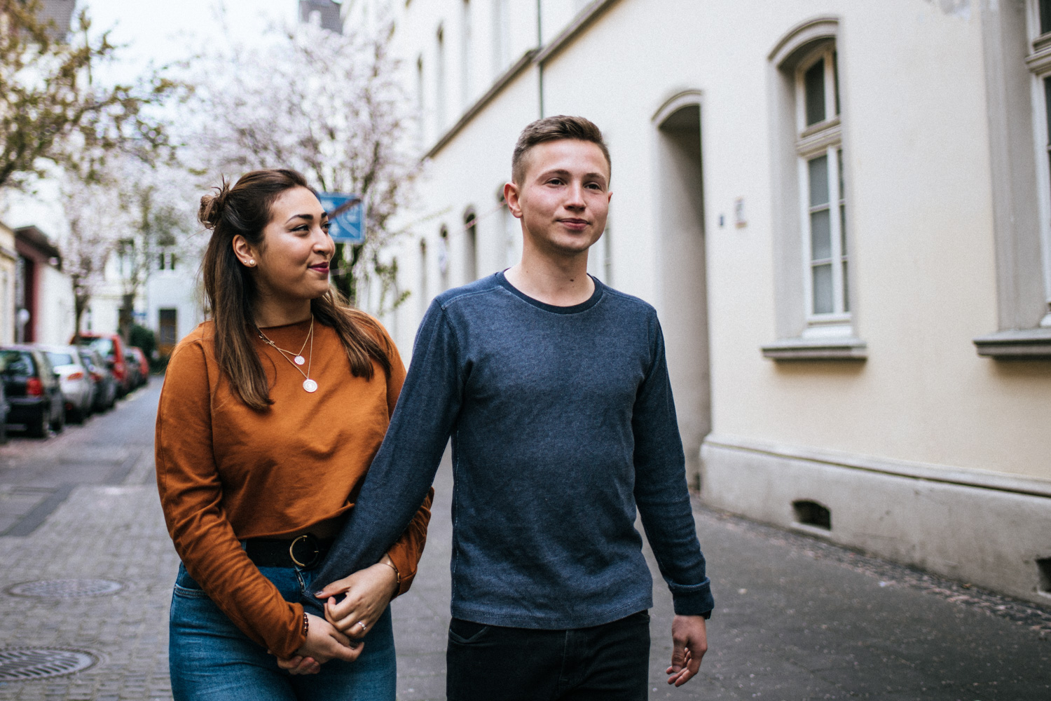 Ein Hand in Hand spazierendes Paar in der Bonner Altstadt beim Fotoshooting.
