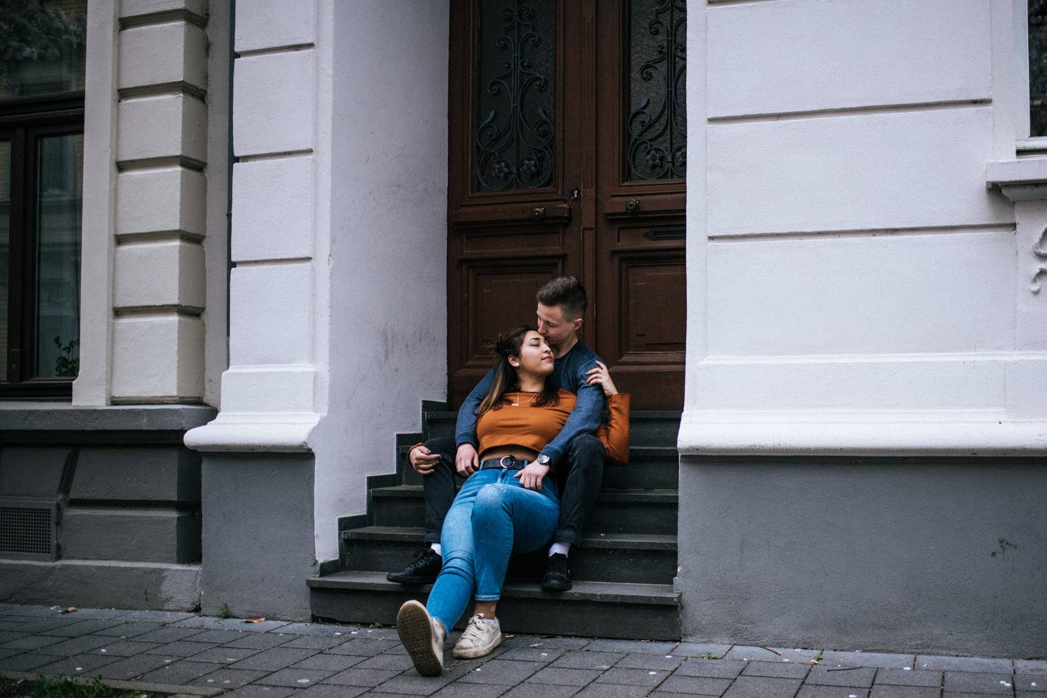 Ein Paar kuschelt auf einer Treppe beim Paarshooting in Bonn.