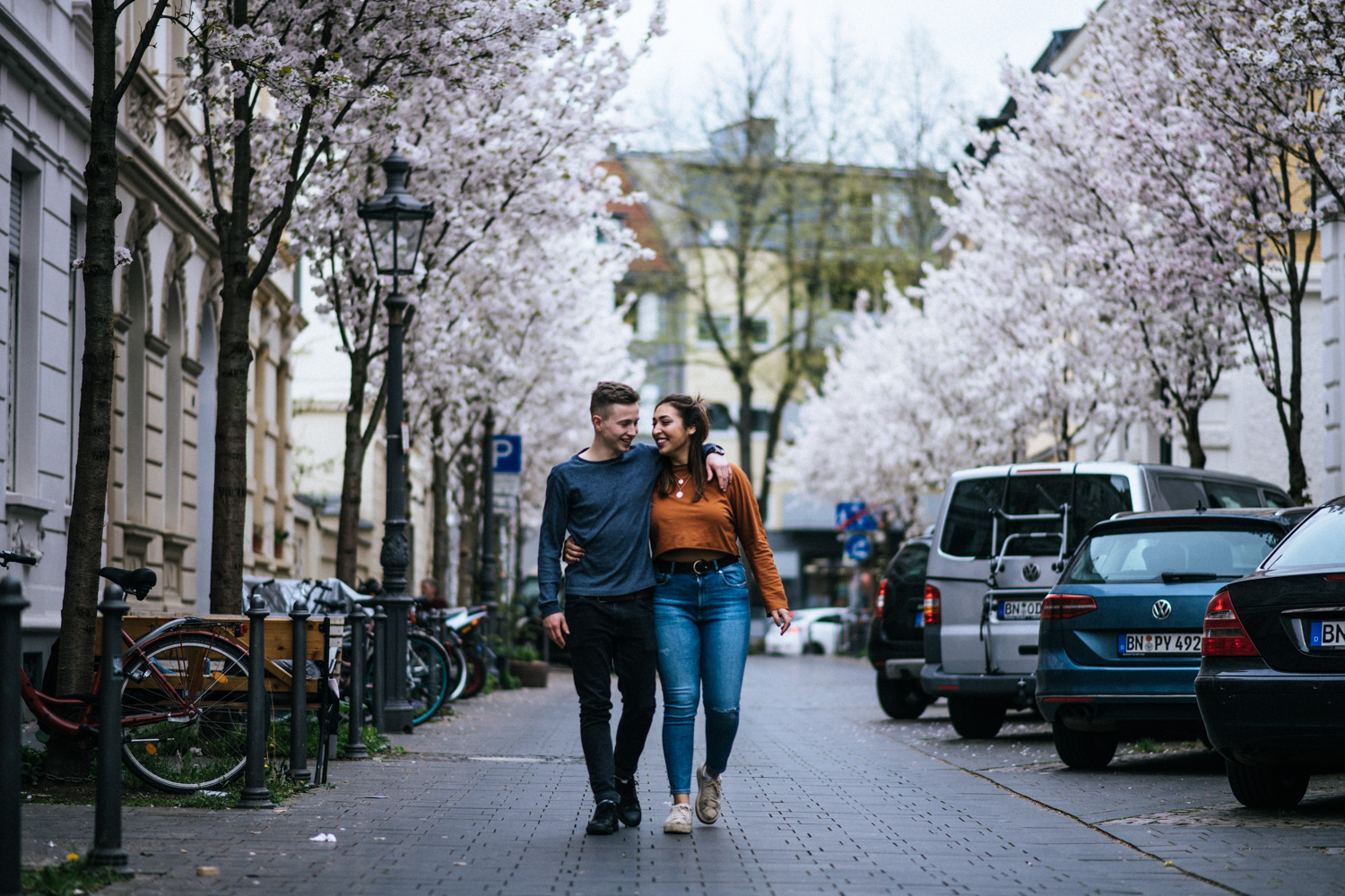 Ein Hand in Hand spazierendes Paar in der Bonner Altstadt beim Fotoshooting.