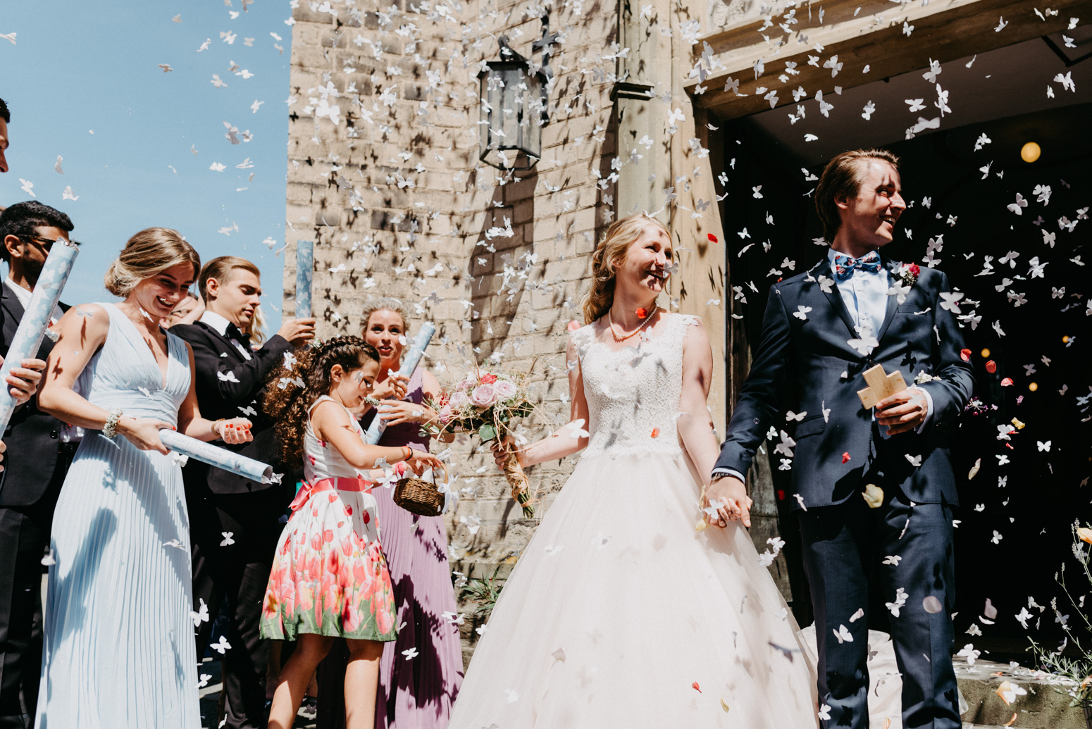 Fliegendes Konfetti beim Auszug des Brautpaares aus der Kirche. Hochzeitsfotografin Daria Becker von Genuine Bonds aus Bonn